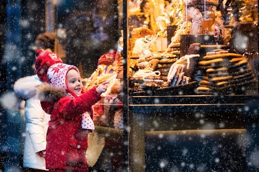 Kids siblings looking at candy and pastry on Christmas market
