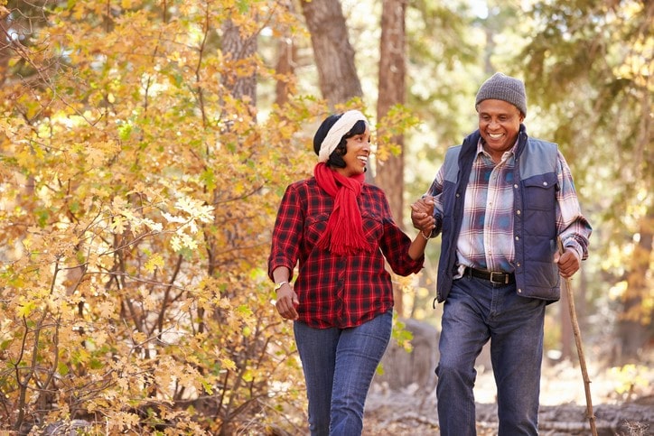 Senior Couple Walking Through Fall Woodland