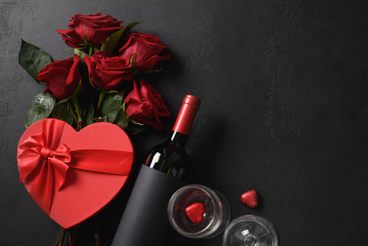 Valentine's day gift, red wine, bouquet of roses on black background.