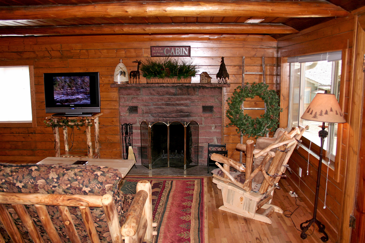 Living room with brick fireplace in wooden panel cabin