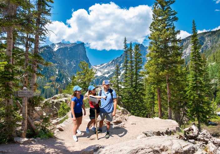 Smiling happy family relaxing on the hiking trail. Smiling people enjoying time together in the mountains on Emerald trail. Estes Park, Rocky Mountains National Park, Colorado, USA.