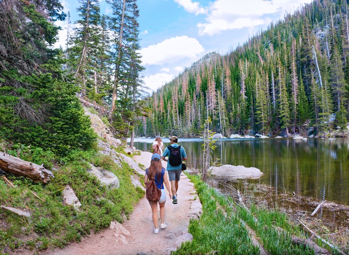 Family on summer vacation trip in the mountains. People hiking on Emerald Lake Trail, next to Dream Lake. Friends exploring Colorado mountains. Rocky Mountains National Park, Colorado, USA.