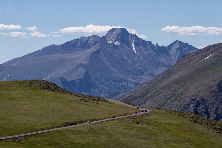 Cars traveling down Trail Ridge road in Rocky Mountain National Park with Longs Peak in the background