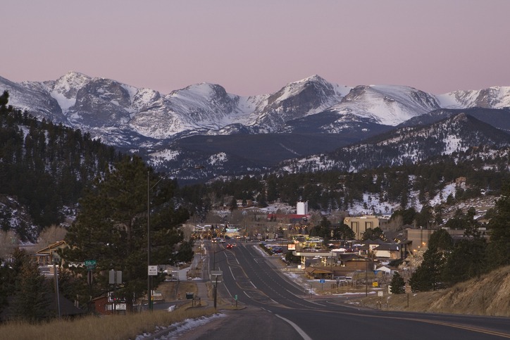 As Highway 34 leads to downtown Estes Park Colorado, morning light begins to warm Powell Peak, Taylor Peak, Hallett Peak, Flattop Mountain and the other mountains along the Continental Divide in Rocky Mountain National Park.